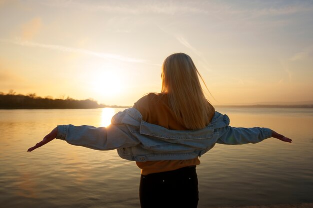 Mulher de tiro médio posando ao pôr do sol