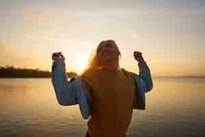 Foto grátis mulher de tiro médio posando ao pôr do sol