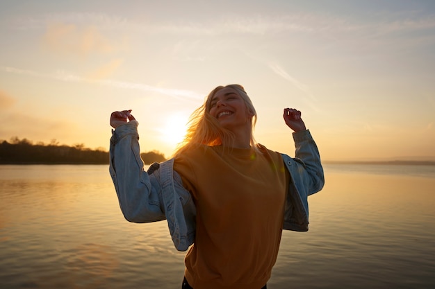 Mulher de tiro médio posando ao pôr do sol