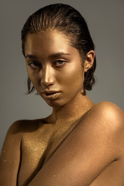Foto grátis mulher de tiro médio posando com pintura corporal dourada