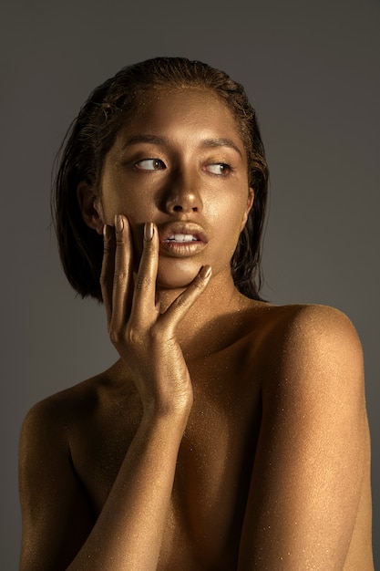 Mulher de tiro médio posando com pintura corporal dourada