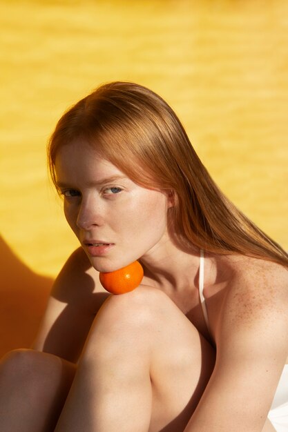 Mulher de tiro médio posando com tangerina