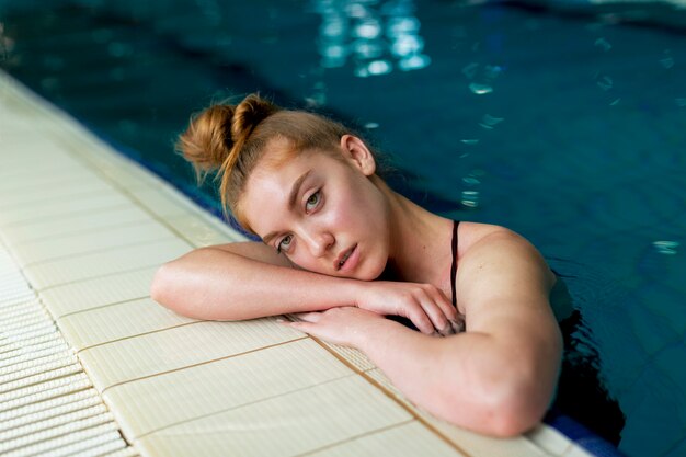 Mulher de tiro médio posando na piscina