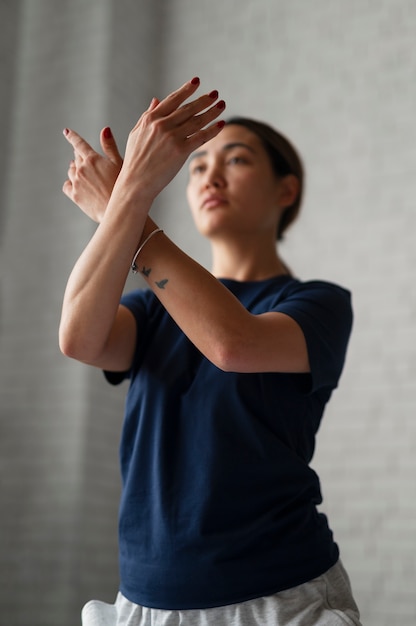 Mulher de tiro médio praticando tai chi dentro de casa