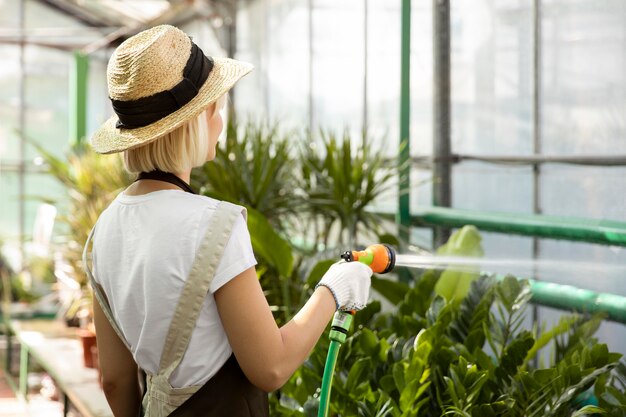 Mulher de tiro médio regando plantas