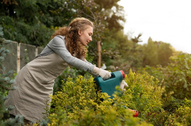 Mulher de tiro médio regando plantas