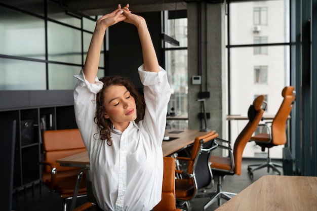 Mulher de tiro médio se alongando no trabalho