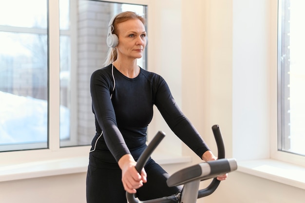 Mulher de tiro médio se exercitando em uma bicicleta de spinning