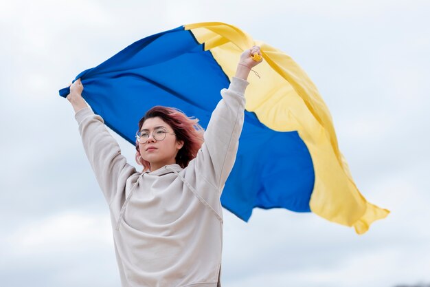 Mulher de tiro médio segurando a bandeira ucraniana