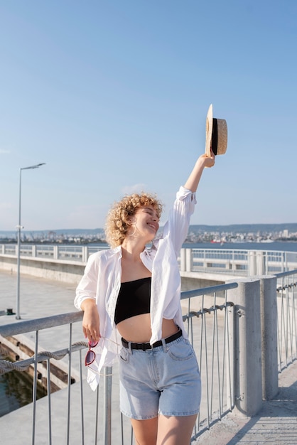 Mulher de tiro médio segurando chapéu