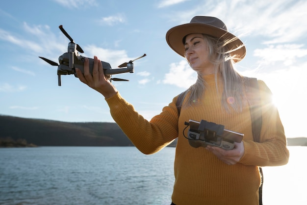 Mulher de tiro médio segurando drone e controle remoto