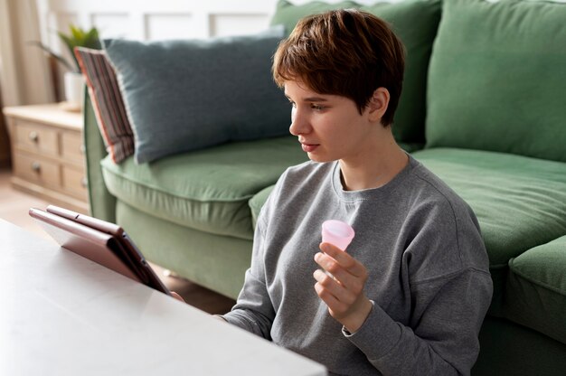 Mulher de tiro médio segurando o copo menstrual rosa