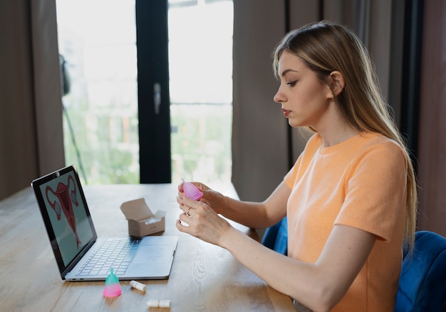 Mulher de tiro médio segurando o copo menstrual