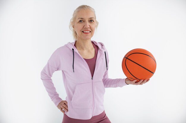 Mulher de tiro médio segurando uma bola de basquete