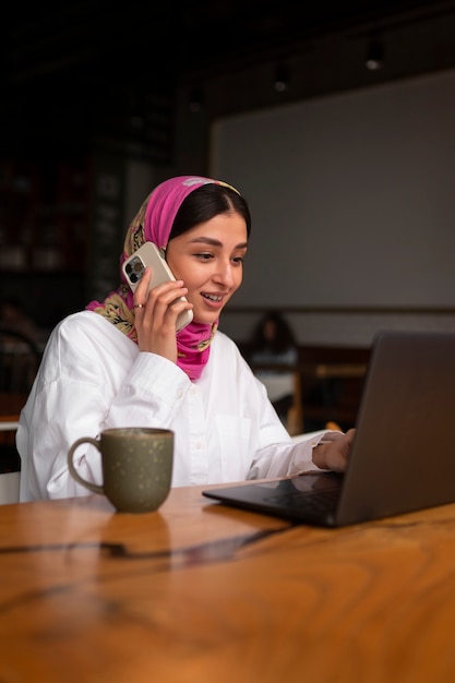 Foto grátis mulher de tiro médio trabalhando com hijab dentro de casa