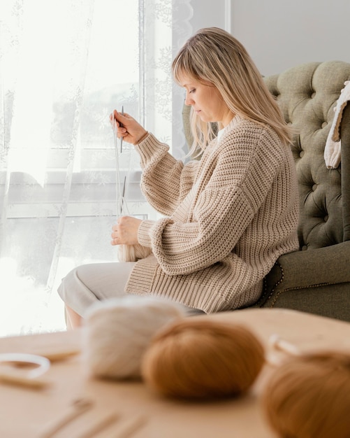 Foto grátis mulher de tiro médio tricotando dentro de casa