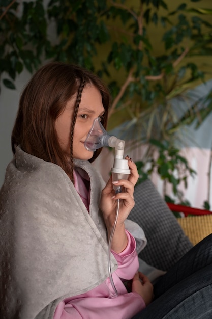Mulher de tiro médio usando nebulizador em casa