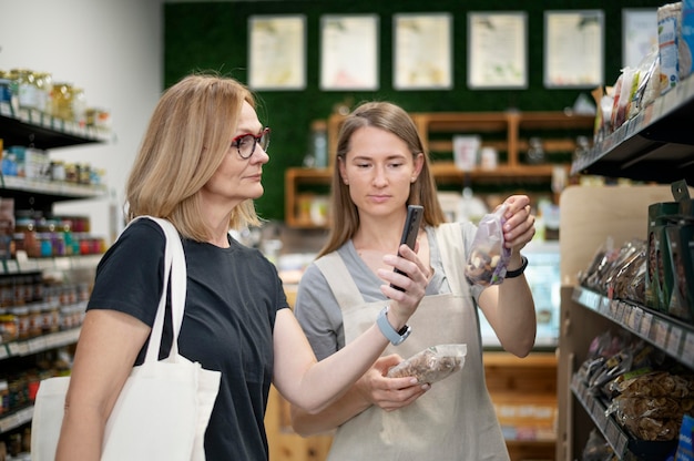 Mulher de tiro médio verificando o produto com o telefone