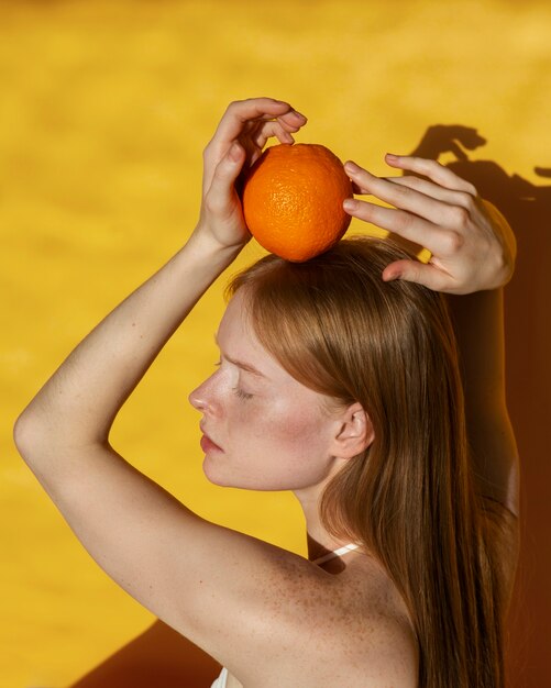 Mulher de tom médio posando com laranja