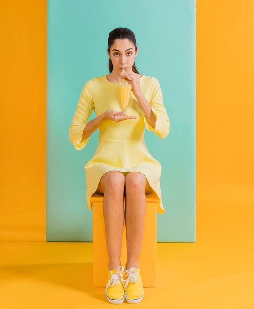 Mulher de vestido amarelo com suco