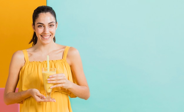 Mulher de vestido amarelo com um copo de suco