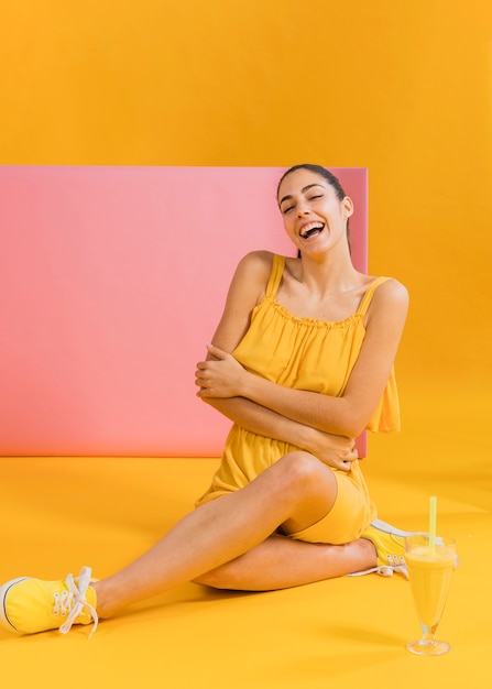 Foto grátis mulher de vestido amarelo com um copo de suco