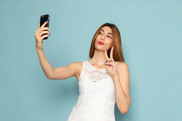 Mulher de vestido branco tirando uma selfie