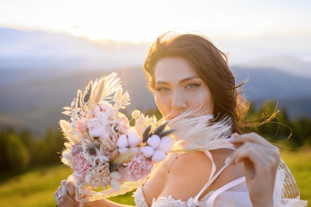 Mulher de vestido de noiva com um monte de flores sobre fundo de paisagens ensolaradas