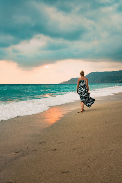 Mulher de vestido longo caminhando na praia