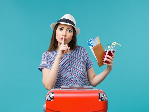 Mulher de vista frontal em férias segurando suco com ingressos no fundo azul viagem viagem avião marítimo feminino verão