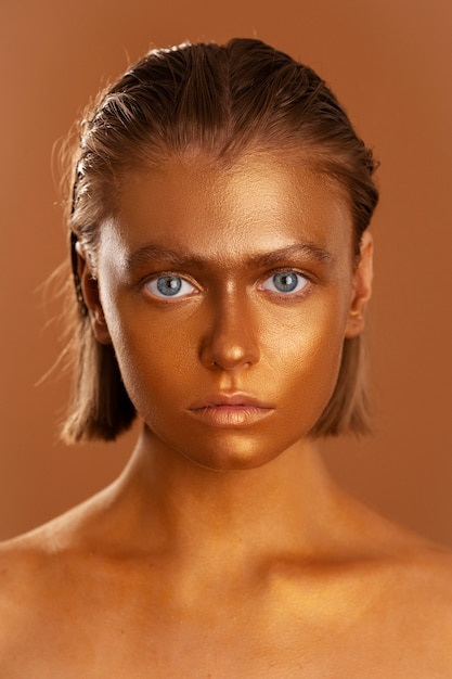 Foto grátis mulher de vista frontal posando com pintura corporal de ouro