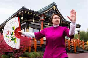 Foto grátis mulher de vista frontal praticando tai chi ao ar livre