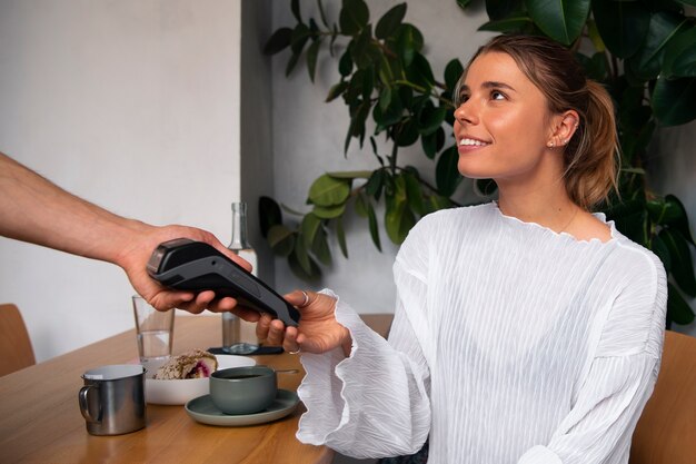 Mulher de vista lateral a pagar com um dispositivo NFC