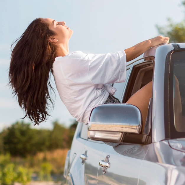 Foto grátis mulher de vista lateral encostada na janela do carro