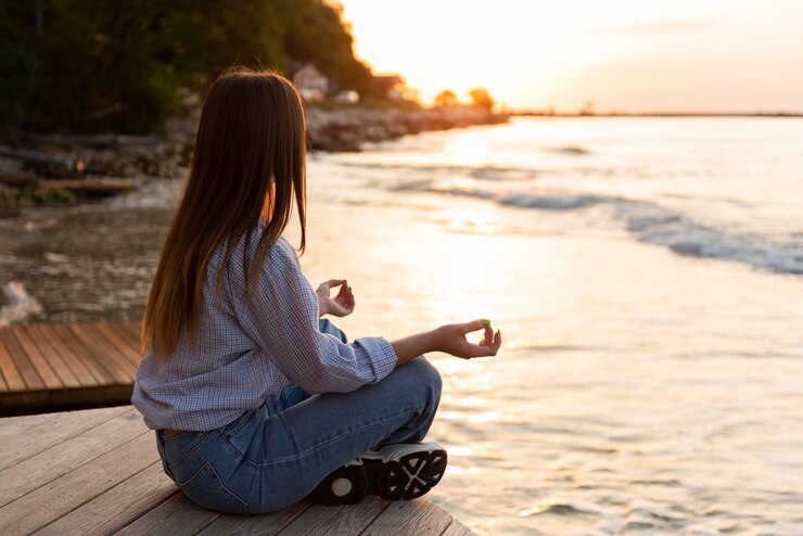 Foto grátis mulher de vista lateral olhando para o mar ao pôr do sol com espaço de cópia