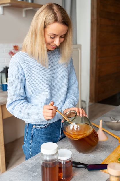 Foto grátis mulher de vista lateral preparando kombucha