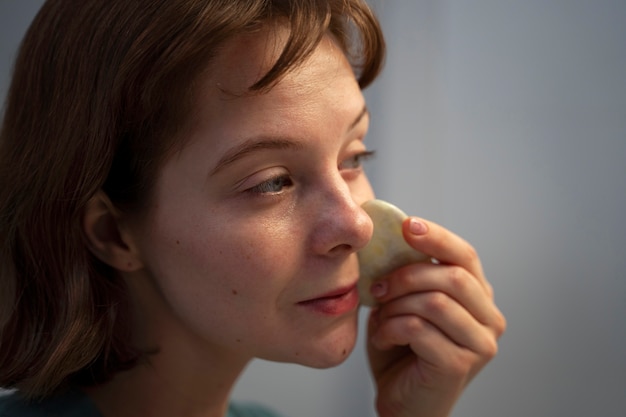 Foto grátis mulher de vista lateral usando gua sha para massagem