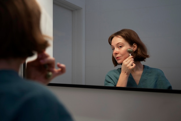 Foto grátis mulher de vista lateral usando rolo facial para massagem