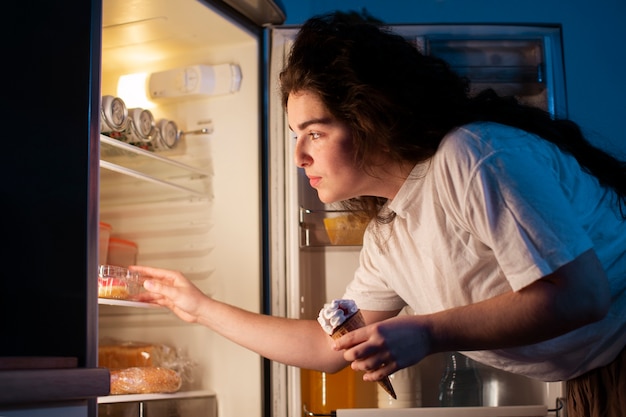 Foto grátis mulher de vista lateral verificando a geladeira
