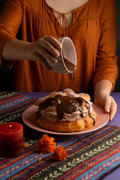 Foto grátis mulher decorando pan de muerto com calda de chocolate em ângulo alto