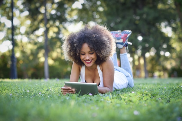 Mulher deitada no gramado de um parque com um laptop