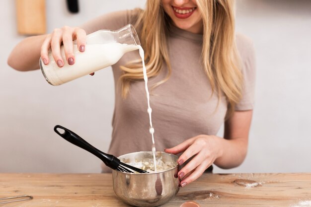 Mulher derramando leite em uma tigela metálica