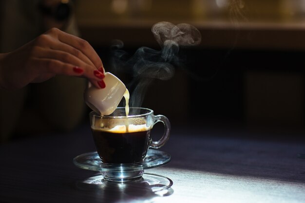 Mulher derramando o leite em seu café