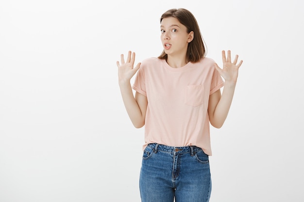 Mulher desajeitada e não envolvida levantando as mãos em sinal de rendição, parecendo sem noção, não sabe de nada