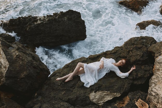 Mulher descalça com vestido de noiva branco na praia do mar cabelo molhado conceito de férias