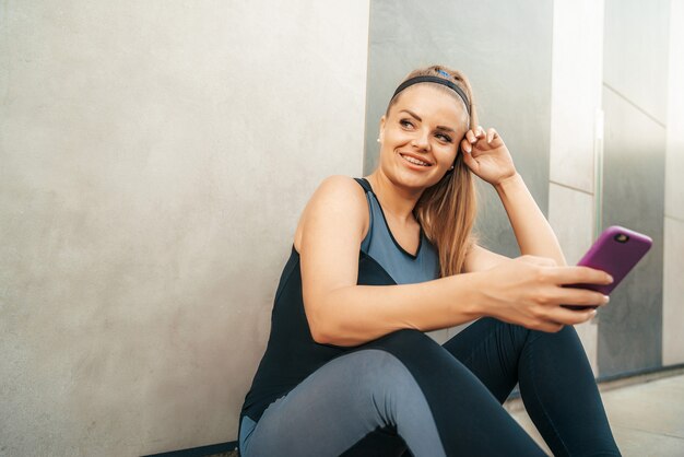 Mulher descansando no sportswear com smartphone