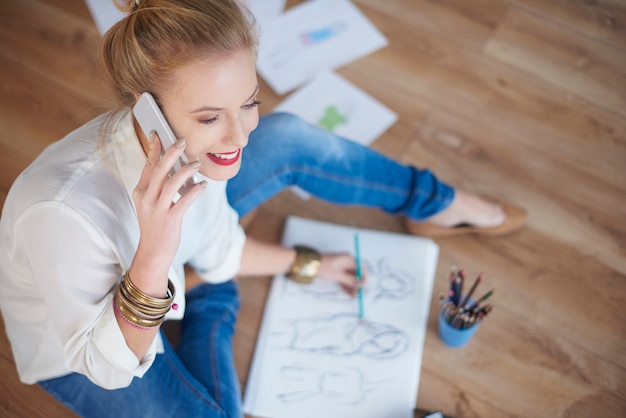 Mulher desenhando esboços e falando ao telefone