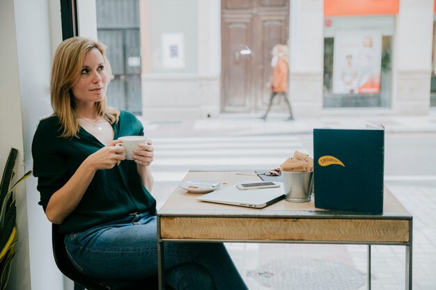 Mulher, desfrutando, café, perto, café, janela