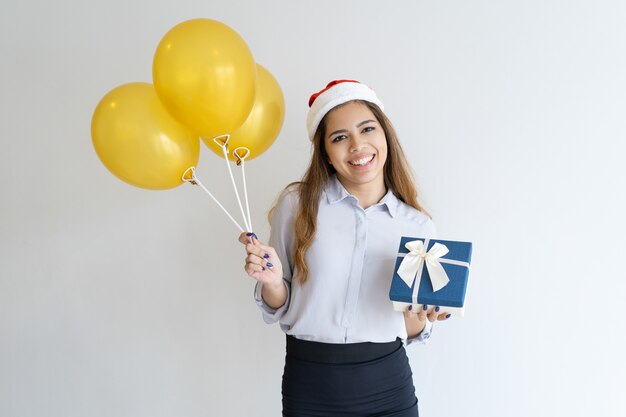 Mulher, desgastar, papai noel, chapéu, e, segurando, caixa presente, e, balões