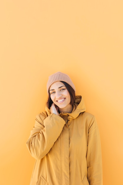 Foto grátis mulher, desgastar, tricotado, chapéu, olhar, câmera, ficar, contra, fundo amarelo